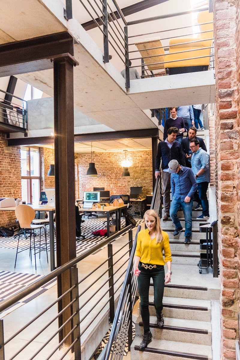 Open-concept office with brick walls, multi-level layout, and team members working together.